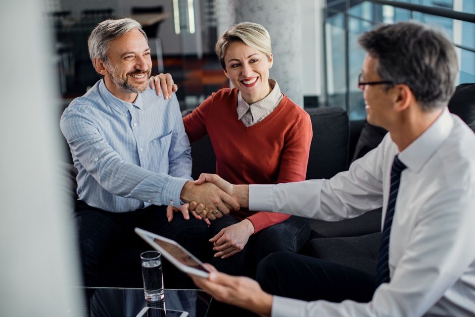 Couple shaking hands with financial adviser